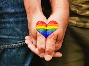 Rainbow heart drawing on hands, LGBTQ love symbol