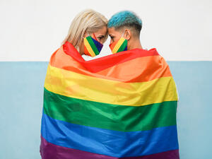 Young couple of women hugging under rainbow flag