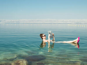 Girl reading newspaper floating on surface Dead Sea 
