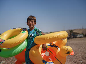 unidentified child walks along the beach to sell swimming rings
