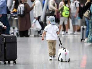 A little boy walks with his suitcase