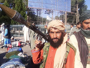 In this picture taken on August 13, 2021, a Taliban fighter holds a rocket-propelled grenade (RPG) along the roadside in Herat, Afghanistan's third biggest city, after government forces pulled out the day before following weeks of being under siege.