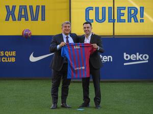 Newly-appointed FC Barcelona's Spanish coach Xavi Hernandez (R), flanked by FC Barcelona's Spanish president Joan Laporta, poses with his jersey during the presentation ceremony at the Camp Nou stadium in Barcelona on November 8, 2021. (Photo by LLUIS GENE / AFP)