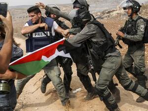 Israeli soldiers arrest a Palestinian journalist