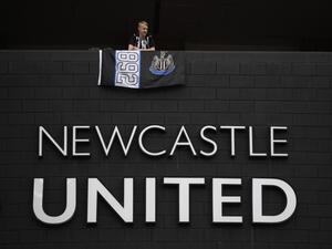 A Newcastle United football club supporter stands with a flag above the club logo at their stadium St James' Park in Newcastle upon Tyne in northeast England on October 8, 2021. (Photo by Oli SCARFF / AFP) A Newcastle United football club supporter stands with a flag above the club logo at their stadium St James' Park in Newcastle upon Tyne in northeast England on October 8, 2021. (Photo by Oli SCARFF / AFP)