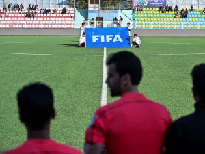 Youths hold a banner with the FIFA emblem before the start of a football match between Shaheen Asmayee and the Abasin Sape during the Amn Tournament, which includes six Afghan Premier League clubs, at Afghanistan Football Federation Stadium in Kabul on November 5, 2021. (Photo by Hector RETAMAL / AFP)
