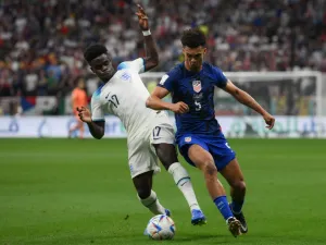 England's forward #17 Bukayo Saka (L) and USA's defender #05 Antonee Robinson fight for the ball during the Qatar 2022 World Cup Group B football match between England and USA at the Al-Bayt Stadium in Al Khor, north of Doha on November 25, 2022. (Photo by Paul ELLIS / AFP)