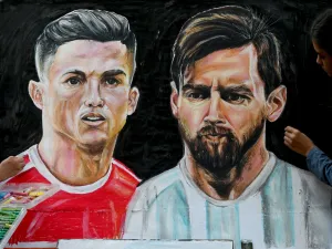 An art school student gives final touches to painting of football players Portugal's Christiano Ronaldo (L) and Argentina's Lionel Messi ahead of the Qatar 2022 World Cup football tournament in Mumbai on November 18, 2022. (Photo by INDRANIL MUKHERJEE / AFP)