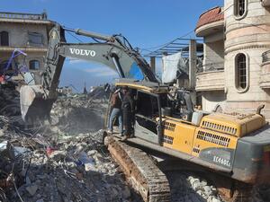 Syrian rescuers use an excavator to shift through the rubble 