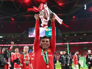 Manchester United's Brazilian midfielder Casemiro holds the trophy as Manchester United players celebrate their win on the pitch after the English League Cup final football match between Manchester United and Newcastle United at Wembley Stadium, north-west London on February 26, 2023. Manchester United clinched their first major trophy for six years with a ruthless 2-0 win against Newcastle in the League Cup final at Wembley on Sunday. (Photo by Glyn KIRK / AFP)