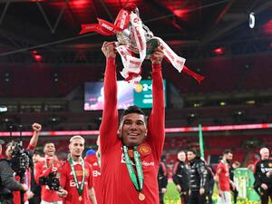 Manchester United's Brazilian midfielder Casemiro holds the trophy as Manchester United players celebrate their win on the pitch after the English League Cup final football match between Manchester United and Newcastle United at Wembley Stadium, north-west London on February 26, 2023. Manchester United clinched their first major trophy for six years with a ruthless 2-0 win against Newcastle in the League Cup final at Wembley on Sunday. (Photo by Glyn KIRK / AFP)