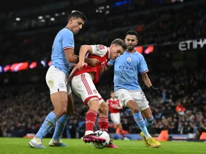 Arsenal's Belgian midfielder Leandro Trossard (C) challenges Manchester City's Spanish midfielder Rodri (L) and Manchester City's Algerian midfielder Riyad Mahrez (R) during the English FA Cup fourth round football match between Manchester City and Arsenal at the Etihad Stadium in Manchester, northwest England, on January 27, 2023. (Photo by Oli SCARFF / AFP)