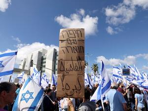 متظاهرون يرفعون لافتة تتهم حكومة نتنياهو بالفاشية (أ ف ب)