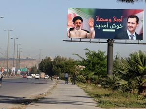 لوحة إعلانية عليها صورة رئيسي والأسدر على طريق المطار في دمشق