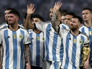 Argentina's forward Lionel Messi (R) waves at the crowd while holding a replica of the World Cup trophy next to his teammates during a recognition ceremony for the World Cup-winning players, following the friendly football match between Argentina and Curacao at the Madre de Ciudades stadium in Santiago del Estero, in northern Argentina, on March 28, 2023. (Photo by Alejandro PAGNI / AFP)