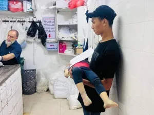 فتى فلسطيني من غزة ينتظر دوره لتكفين أخيه الشهيد- صورة من مواقع التواصل