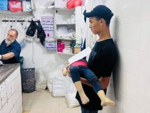 فتى فلسطيني من غزة ينتظر دوره لتكفين أخيه الشهيد- صورة من مواقع التواصل