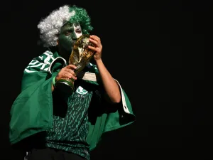 A Saudi Arabia fan kisses a replica of the FIFA World Cup trophy ahead of the Qatar 2022 World Cup Group C football match between Poland and Saudi Arabia at the Education City Stadium in Al-Rayyan, west of Doha on November 26, 2022. (Photo by Glyn KIRK / AFP)