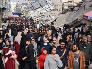 Crowds of people walk past destroyed buildings in the southern Gaza Strip city of Khan Yunis on November 28, 2023. (Mohammed Abed/ AFP)