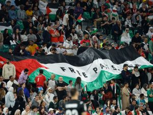 علم فلسطين يرفرف خلال مباراة إيران وفلسطين (Photo by KARIM JAAFAR / AFP)