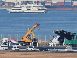 Officials remove the remaining debris of a Japan Airlines (JAL) (Photo by Richard A. BROOKS / AFP) plane crashes