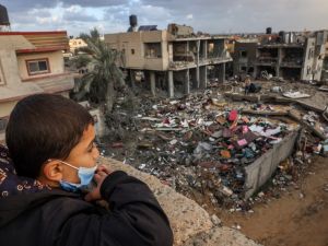 A Palestinian child looks on as people stand on the rubble of a building destroyed during Israeli strikes on Rafah, on the southern Gaza Strip, on November 20, 2023, amid continuing battles between Israel and the militant group Hamas. (Photo by Mohammed ABED / AFP) Gaza