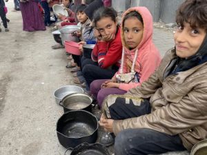 أطفال ينتظرون دورهم للحصول على بعض الطعام في غزة (الجزيرة)