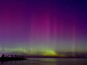 People watch the the aurora australis or southern lights caused by a solar storm at Port Phillip Bay in Melbourne on May 11, 2024. (Photo by Paul CROCK / AFP) Sun