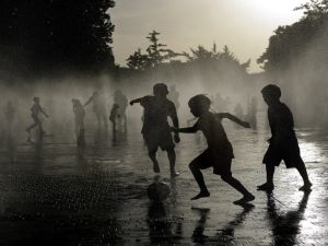 أطفال يلعبون كرة القدم بينما يبردون أجسامهم في نافورة مياه، في ظل موجة حر تضرب إسبانيا
