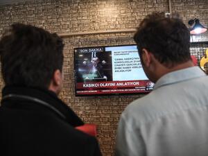 People watch on a TV the speech of Turkish president Recep Tayyip Erdogan (AFP)