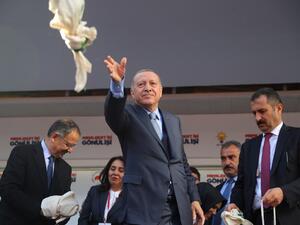 Turkish President and leader of Turkey's ruling Justice and Development (AK) Party Recep Tayyip Erdogan throws bags of tea to his supporters. (Adem ALTAN / AFP)