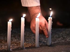 A well-wisher places one of 49 candles as he pays respects to victims outside the hospital in Christchurch (AFP)