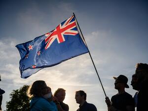 A man raises a New Zealand flag as he attends a vigil in memory of the twin mosque massacre victims in Christchurch (AFP)