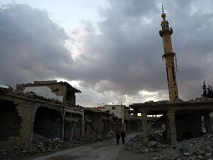 Syrian children walk past heavily damaged buildings in the rebel-held town of Douma, on the eastern edges of the capital Damascus on February 27, 2016, on the first day of the landmark ceasefire agreement. (AFP/Sameer al-Doumy)