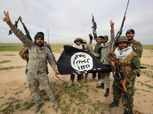 Iraqi Shia fighters from the Popular Mobilization units pose with a Daesh group flag on March 3, 2016, during an operation in the desert of Samarra aimed at retaking areas from militants. (AFP/Ahmad al-Rubaye)