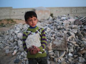 Palestinian Karim holds a rock as he helps his mother load it into their donkey-pulled cart in Khan Yunis in the southern Gaza Strip, on March 10, 2016. (AFP/Said Khatib)