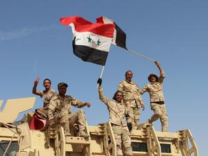 Iraqi government forces wave their national flags on March 10, 2016 after retaking the town of Zankura, northwest of Ramadi, from Daesh in Anbar province. (AFP/Moadh al-Dulami)
