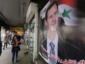 Syrians walk past a portrait of President Bashar al-Assad in the capital Damascus on March 15, 2016. (AFP/Louai Beshara)
