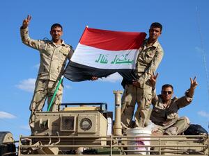 Iraqi government forces wave the national flag from their vehicles in the village of Mohammadi, a few miles north of Hit, in Iraq's western province of Anbar on March 18, 2016. (AFP/Moadh al-Dulaimi)