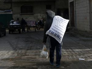 A Palestinian youth carries food donations outside the United Nations food distribution center in Gaza City on Jan. 15, 2018 (MOHAMMED ABED / AFP)
