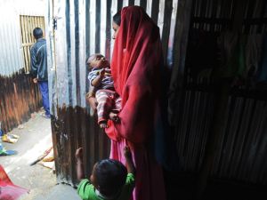 A Rohingya refugee carrying a baby stands at a temporary shelter near the village of Baruipur, some 55km south of Kolkata on Jan. 19, 2018 (Dibyangshu SARKAR / AFP)