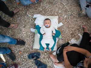 A Syrian baby lies in gravel at Kara Tepe camp, where its parents are unable to feed it. (Facebook)