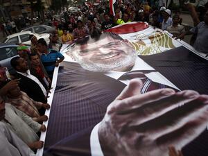 Ousted President Mohamed Morsi supporters and Muslim Brotherhood members hold a giant portrait of him as they demonstrate against his toppling at Raba al-Adwyia mosque on July 7, 2013 in Cairo.
(AFP/File)