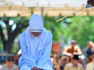 The young woman clenches her fists in anticipation as the cane is brought down across her back (AFP)