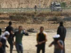 An Israeli soldier aims his weapon as Palestinian protesters gather near the border fence with Israel (AFP/File Photo)	