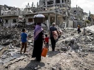 A displaced Palestinian family walks through a northern Beit Hanun neighborhood in the Gaza Strip. (AFP/File)