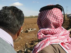 Jordanians stare at a car, submerged in mud following flash floods (AFP)