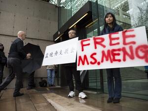 Robert Long (L) and Ada Yu hold signs in favor of Huawei Technologies Chief Financial Officer Meng Wanzhou outside her bail hearing at British Columbia Superior Courts following her December 1 arrest in Canada for extradition to the US, in Vancouver, British Columbia on December 11, 2018. 
Jason Redmond / AFP