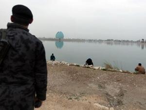 An Iraqi police officer looks at people fishing by the Tigris river facing the Shahid (martyr) Monument. (AFP PHOTO/PATRICK BAZ)