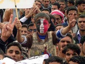 An Iraqi boy, whose face is made up with the national flag, flashes the sign of victory during a rally following the Friday's prayers to call for the government's fall. (AFP PHOTO/MARWAN IBRAHIM)